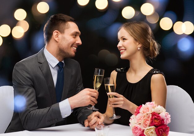 restaurante, pareja y concepto de vacaciones - pareja sonriente con una copa de champán mirándose en el restaurante