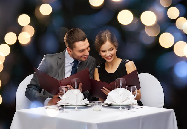 restaurante, pareja y concepto de vacaciones - pareja sonriente con menús en el restaurante