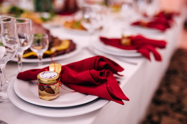 Restaurante Sirviendo banquetes Catering Cena de bodas Coloque la mesa con platos blancos y servilletas rojas con un pequeño tarro de miel y nueces