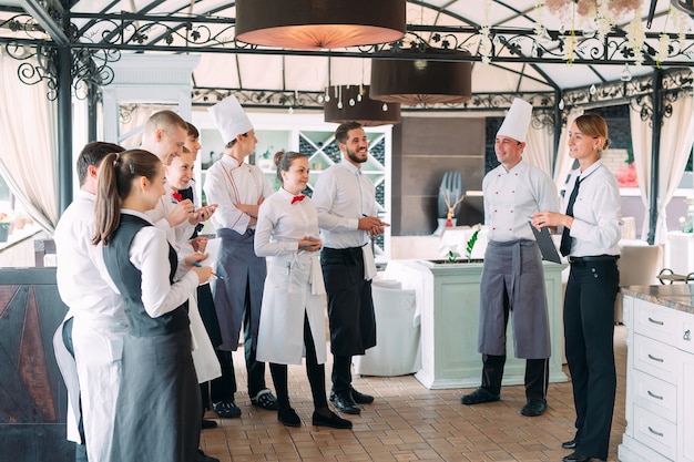 Restaurantmanager und seine Mitarbeiter auf der Terrasse im Austausch mit dem Küchenchef im Restaurant,