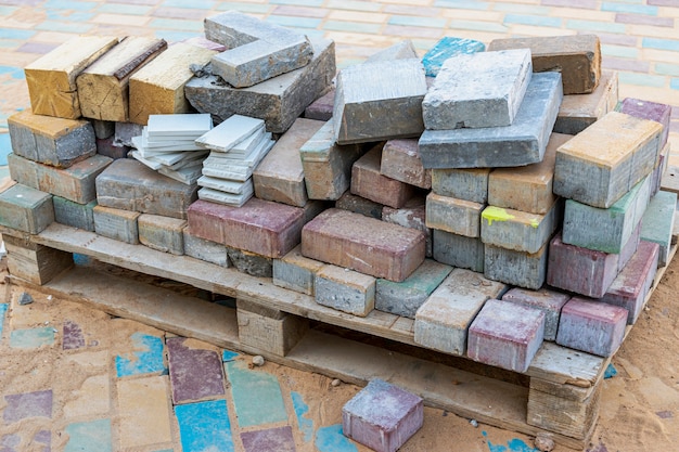 Restos de lajes de pavimentação de concreto multicolorido em um palete após o assentamento da passarela.