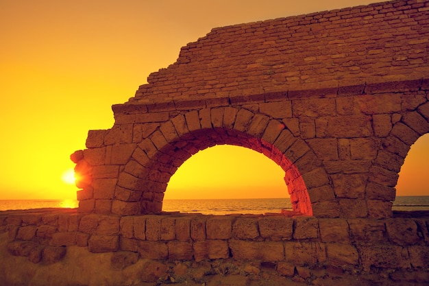 Restos do antigo aqueduto romano na antiga cidade de Cesaréia ao pôr do sol, Israel