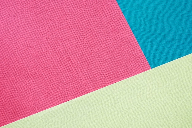 Foto resumen de antecedentes y textura. tres hojas de papel de textura multicolor rosa, azul y amarillo claro.