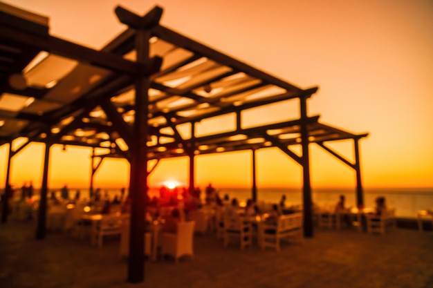 Resumen imagen borrosa de la terraza del restaurante al aire libre en la cálida noche de verano atardecer sobre el mar con