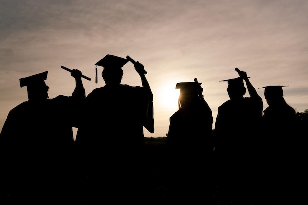 Resumo Fechar o grupo de visão traseira dos graduados universitários no pôr do sol Silhouette