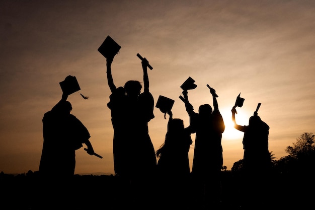 Foto resumo fechar o grupo de visão traseira dos graduados universitários no pôr do sol silhouette