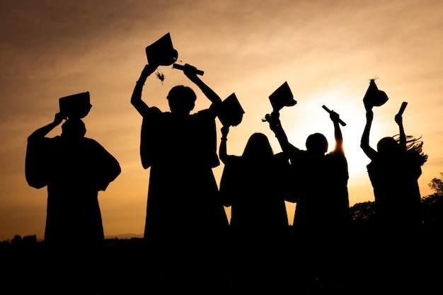 Foto resumo fechar o grupo de visão traseira dos graduados universitários no pôr do sol silhouette