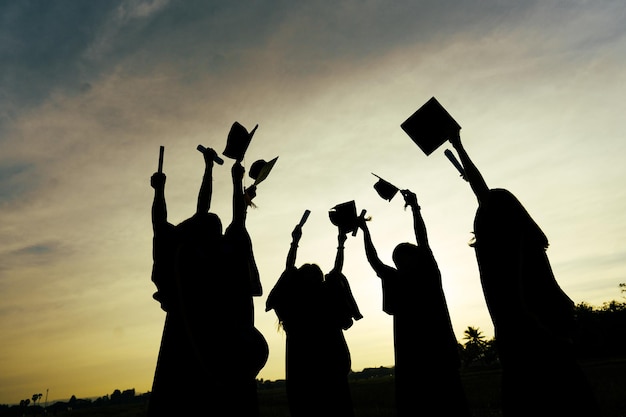 Foto resumo fechar o grupo de visão traseira dos graduados universitários no pôr do sol silhouette