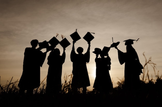 Foto resumo fechar o grupo de visão traseira dos graduados universitários no pôr do sol silhouette