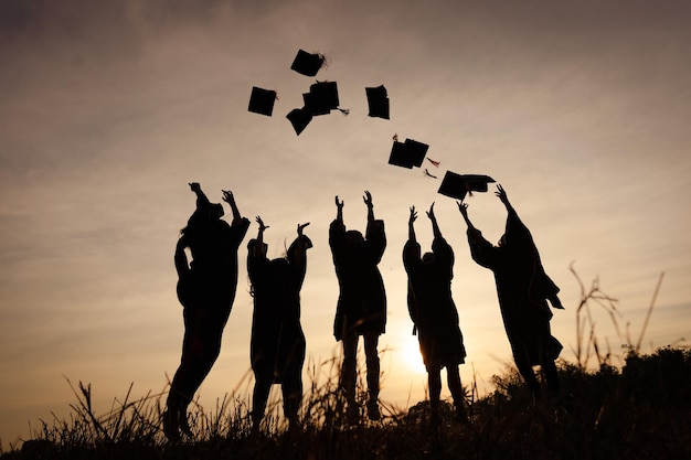 Foto resumo fechar o grupo de visão traseira dos graduados universitários no pôr do sol silhouette