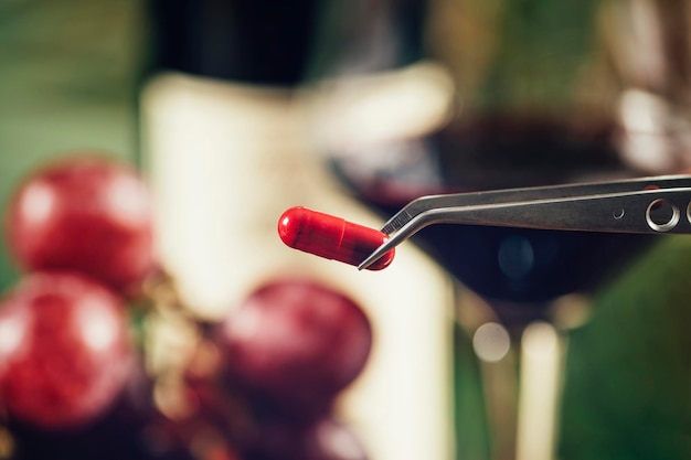 Resveratrol-Ergänzungen mit verschwommenen Trauben und einem Glas Rotwein im Hintergrund