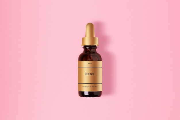 Retinol em um frasco cosmético de vidro marrom Com etiqueta dourada Com uma inscrição Em um fundo rosa