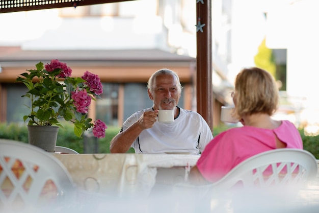 Retirement concepta Älteres Ehepaar trinkt Kaffee auf der Veranda Zwei ältere Männer und Frauen trinken Kaffee und lächeln oder diskutieren Zukunftspläne nach dem Ruhestand