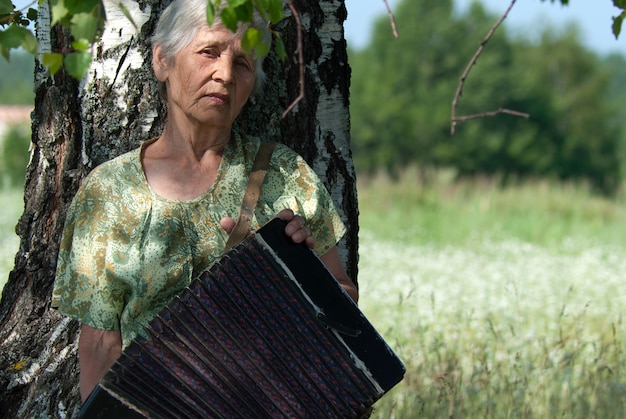 Retrato de abuela con acordeón en verano