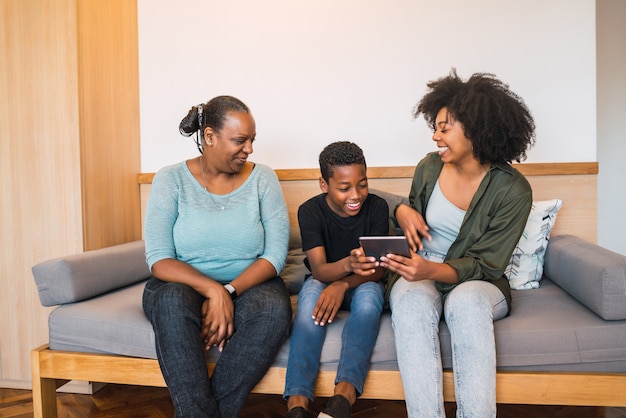 Retrato de abuela afroamericana, madre e hijo con tableta digital en casa