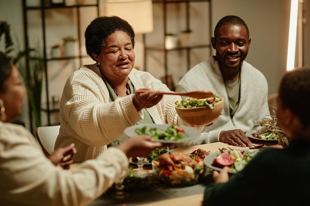 Retrato de abuela afroamericana sonriente que sirve comida mientras celebra el día de acción de gracias con ...
