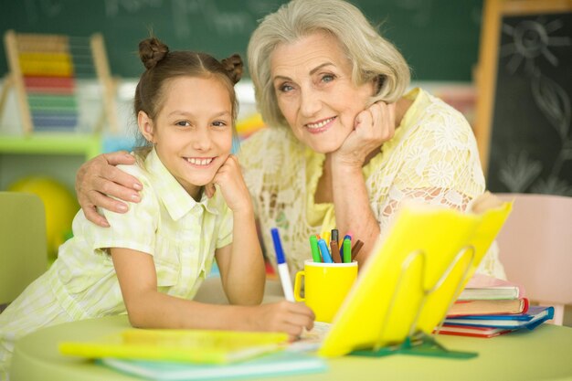 Retrato de una abuela con una niña haciendo los deberes