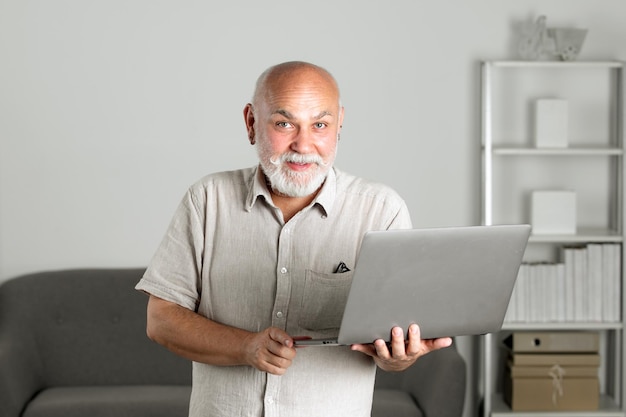 Retrato de abuelo de hombre mayor con una computadora portátil hombre mayor con barba gris en casa hombre maduro usi