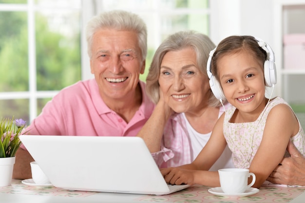 Retrato de abuelos felices y una niña con laptop