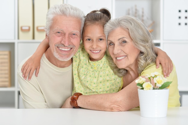 Retrato de abuelos con nieta posando juntos en casa