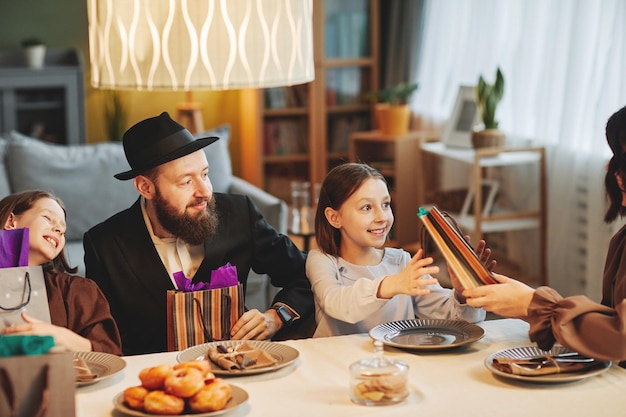 Retrato aconchegante da família judia moderna compartilhando presentes na mesa de jantar enquanto celebra o holi religioso