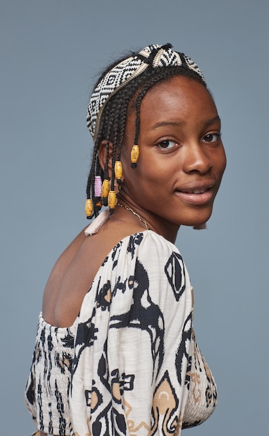 Retrato de una adolescente africana con peinado afro y ropa nacional mirando a la cámara contra