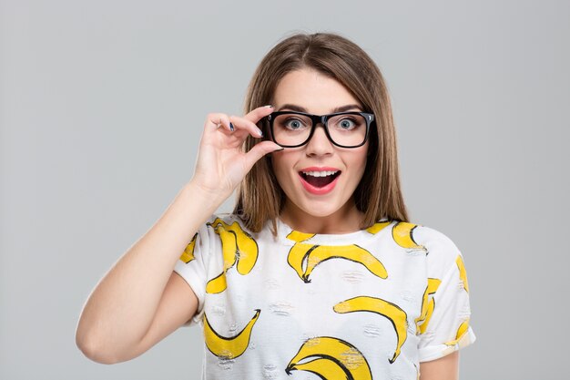 Retrato de una adolescente alegre en gafas mirando a la cámara aislada sobre un fondo blanco.