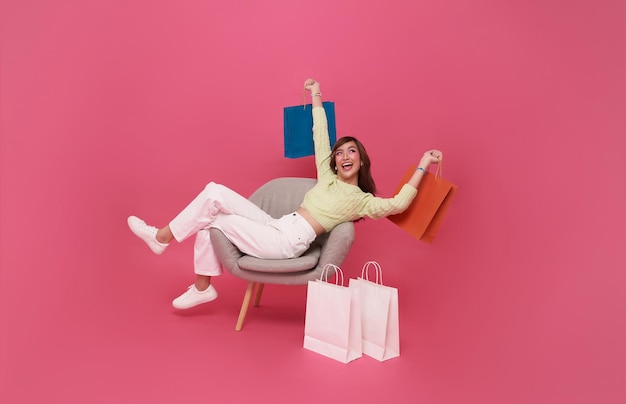 retrato de una adolescente asiática feliz sentada en el sofá con bolsas de compras