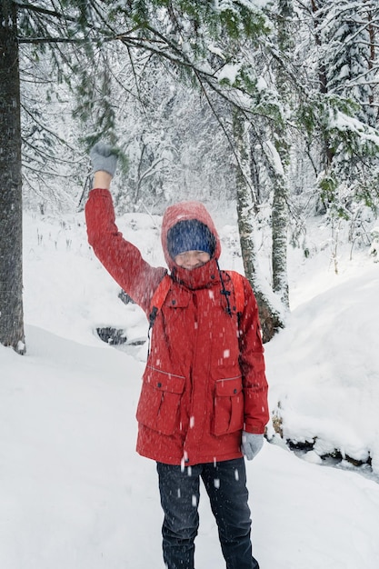 Retrato de adolescente caminando y divirtiéndose en el bosque nevando en invierno