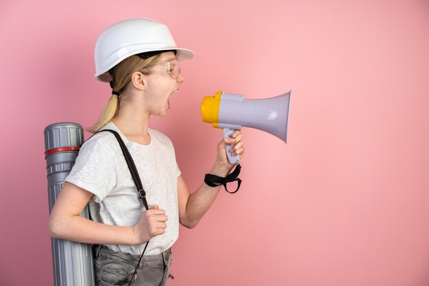 Retrato de una adolescente en un casco, un altavoz en sus manos y un sombrero de copa en la espalda