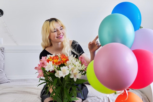 Retrato de una adolescente de cumpleaños con ramo de flores y globos en casa