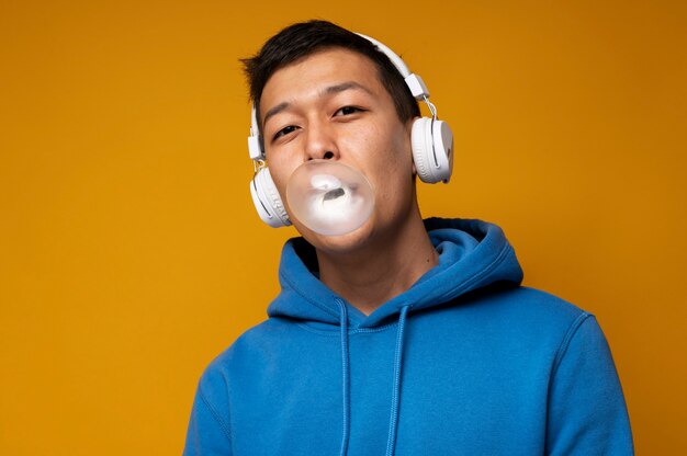 Retrato de un adolescente escuchando música y haciendo estallar un globo