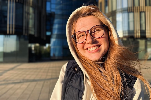 Retrato de una adolescente feliz o una joven universitaria o estudiante universitaria con gafas al aire libre