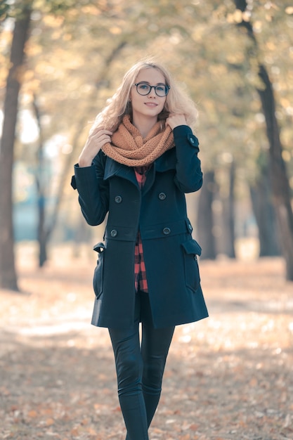 Retrato de una adolescente con grandes gafas negras en un parque de otoño