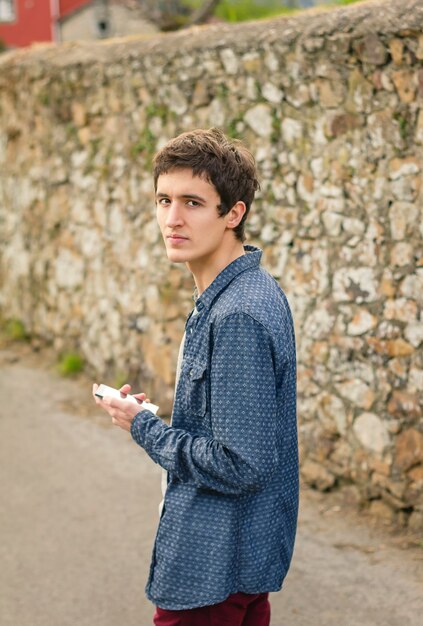 Retrato de adolescente hipster usando su teléfono inteligente al aire libre