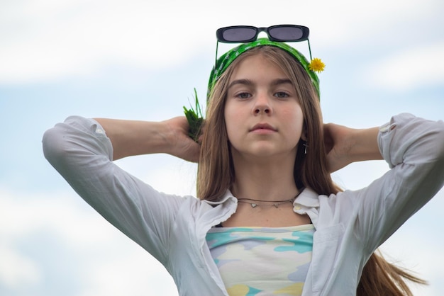 Retrato de una adolescente de moda en un campo de hierba verde con un ramo de flores silvestres