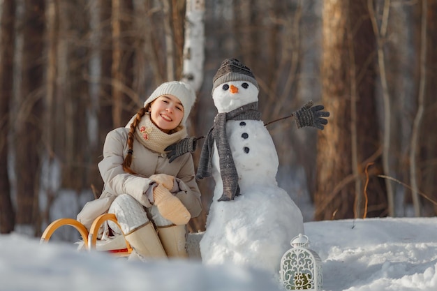 Retrato de una adolescente con un muñeco de nieve en el bosque