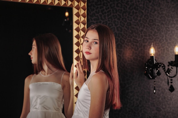 Retrato de una adolescente muy linda con un vestido elegante en el espejo