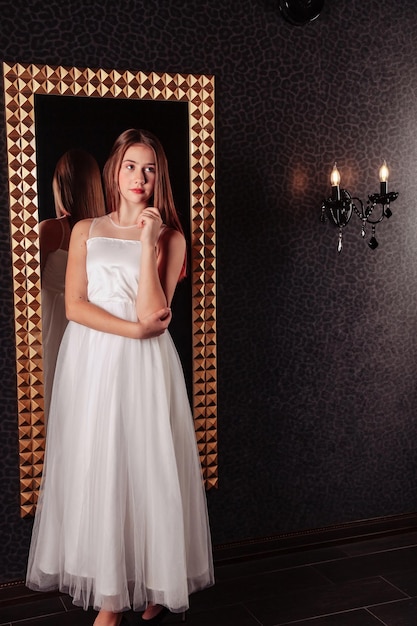 Retrato de una adolescente muy linda con un vestido elegante en el espejo