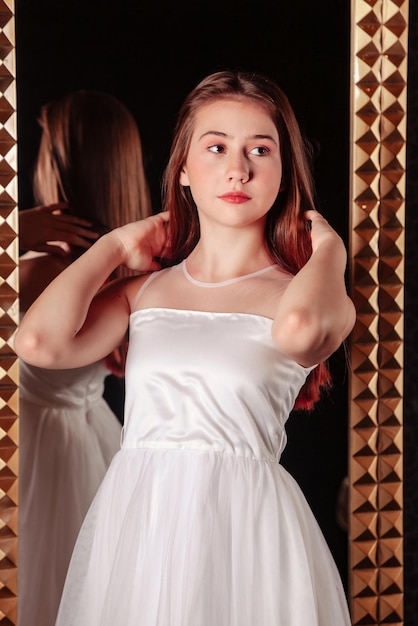 Retrato de una adolescente muy linda con un vestido elegante en el espejo