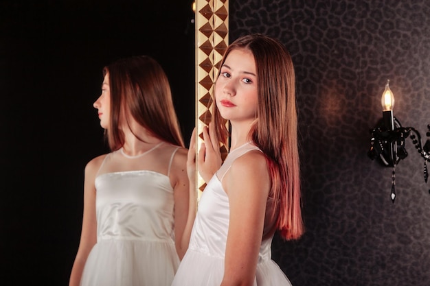 Retrato de una adolescente muy linda con un vestido elegante en el espejo