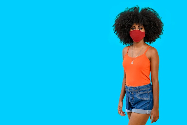 Retrato de una adolescente negra con peinado afro, con protector facial, vestida con ropa informal, aislada de fondo gris.