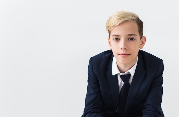 Retrato de adolescente de niño de escuela con estilo en camisa blanca y chaqueta contra fondo blanco con espacio de copia