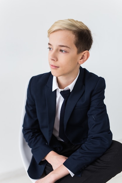 Retrato de adolescente de niño de escuela con estilo en camisa blanca y chaqueta sobre fondo blanco.