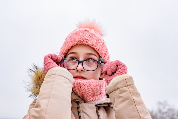 Retrato de una adolescente en el paisaje invernal. En manos de la niña sus gafas. Retrato de invierno