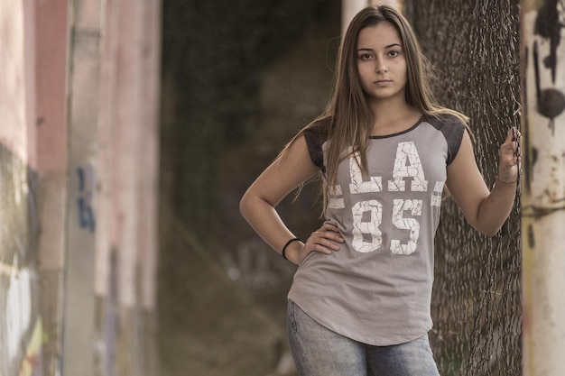 Foto retrato de una adolescente de pie junto a una valla