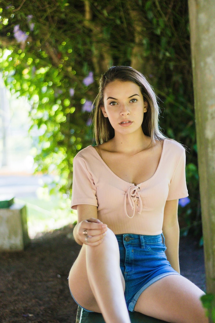Foto retrato de una adolescente sentada contra los árboles en un parque