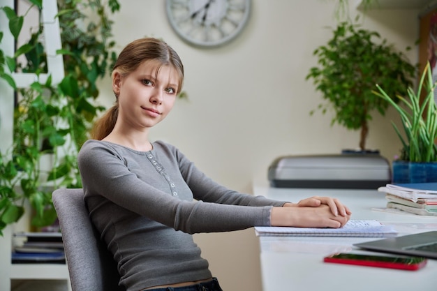 Retrato de una adolescente sentada en su escritorio en casa con una computadora portátil