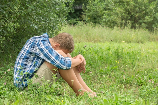 Foto retrato de un adolescente sentado en el césped