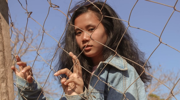 Foto retrato de una adolescente sosteniendo una valla